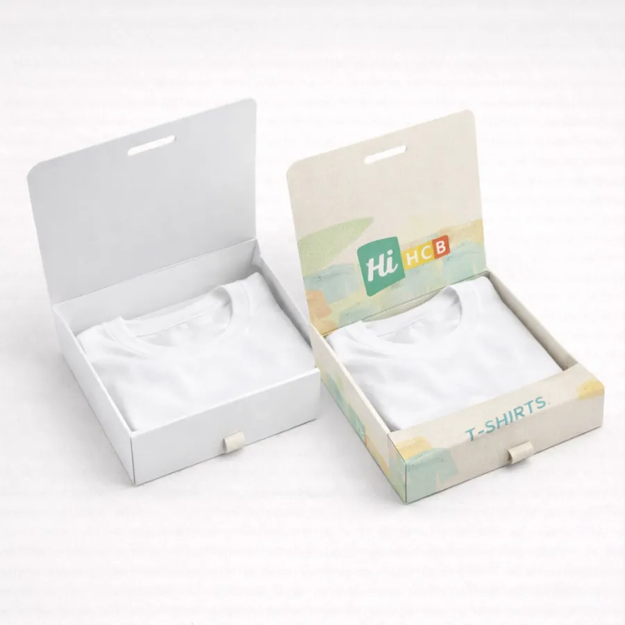 Two shallow t-shirt boxes with hinged lids open- displaying neatly folded white t-shirts inside- class=